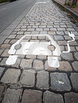 Electric car charging sign painted on paving stones on a city street.