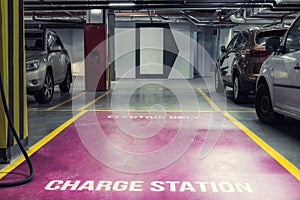 Electric car charging station in underground indoor parking of mall or office building. Reserved parking lot for environment