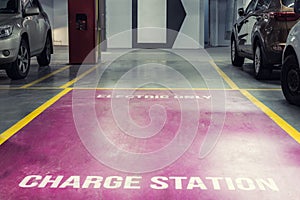 Electric car charging station in underground indoor parking of mall or office building. Reserved parking lot for environment