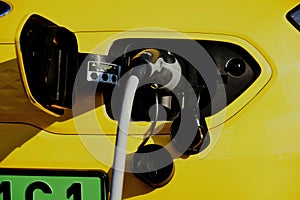 electric car charging station. yellow car detail with industrial grade cable and connecting plug closeup