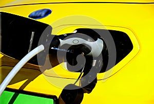 electric car charging station. yellow car detail with industrial grade cable and connecting plug closeup