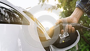 Electric car or ev is charging at station . man use the white power cable and plug on nature background