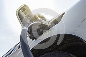 Electric car in EV charging station with sunlight in the background, concept of green energy and eco power produced from