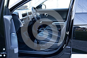 Electric car interior luxury inside. Steering wheel, dashboard, speedometer, display. Black leather interior. Modern