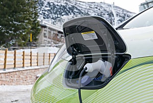 Electric car plug charging in the winter mountain town