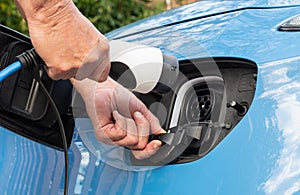 Electric car showing a man's hands connecting a CCS Type 2 charge plug and socket and granny cabl
