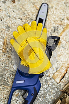 electric chain saw and protective leather work gloves