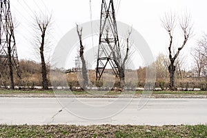 Electric city pole with gray sky and bare tree branches