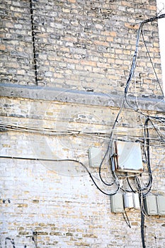 Electric controller box and tangle of cables on brick wall