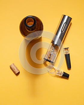 Electric corkscrew made of gray metal. Bottle, aerator, vacuum cork for wine. On a yellow background. Isolated. Hard light and