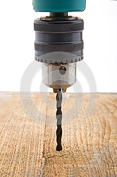 A front view of a metal drill chuck with a spiral drill bit attached to it on an isolated white background