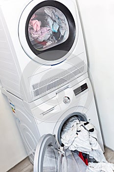 Electric dryer with clothes inside and washer in the laundry room