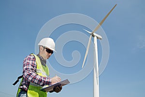 Electric Engineer writing report on Clipboard with Wind turbine