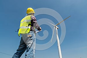 Electric Engineer writing report on Clipboard with Wind turbine