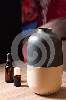 Electric Essential oils Aroma diffuser, oil bottles and flowers on wooden table, space for text
