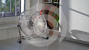 Electric fan with red wriggle ribbon designed to cool air and supply wind located near window