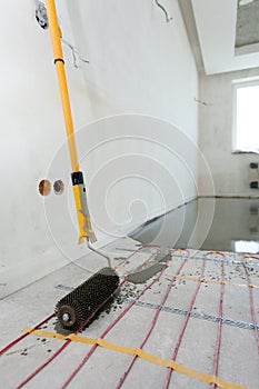 Electric floor heating system installation in new house. Closeup of the rooler for align concrete.