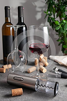 Electric gray metal corkscrew, aerator and vacuum stopper for wine. On a gray concrete background. In the background are two