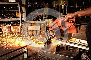 Electric grinder cutting steel. Working man with electric grinder tool in factory with fire sparks.