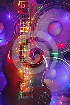 Electric guitar with festive Christmas lights and music speakers in smoke