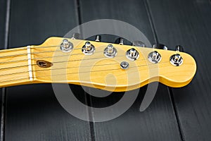 Electric guitar headstock and tuning keys with strings in blondescotch lacquered wood