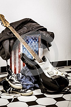 Electric guitar, leather jacket and sports shoes lying on the fl