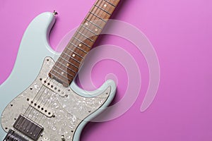 Electric guitar on pink table background, close up music concept