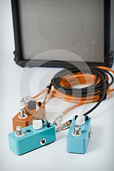 Electric guitar stomp effectors and cables in studio. Focus is on forehand switch box.