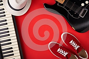 Electric guitar, synthesiser and red stylish sneakers, on red background