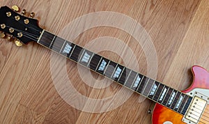 Electric guitar. Top view of a guitar neck body fretboard and headstock against wooden floor background