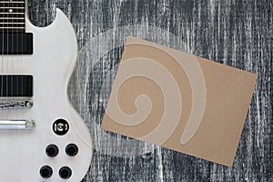 Electric guitar on wooden grey background, sheet of paper