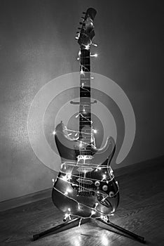 Electric guitar wrapped in colorful garland, the idea of holiday music, black and white photo