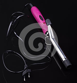 Electric hair curler on black mirror background with copy space