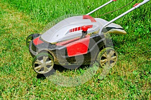 Electric hand lawn mower mows the grass. Close-up. Side view