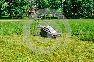 Electric hand lawn mower at the stadium. Lawn care on the sports field