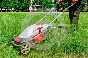 Electric hand lawn mower at the stadium. Lawn care on the sports field