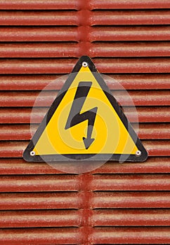 Electric hazard advert sign on a red metal wall background