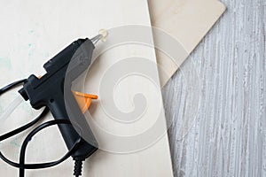 Electric hot glue gun on a wood background. the concept of repair or creativity background