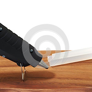 Electric hot glue gun on wooden table isolated on white background