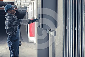 Electric Installation Technician In Front of Main Fuse Box