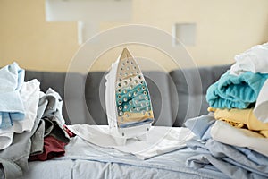 Electric iron and pile of clothes on ironing board