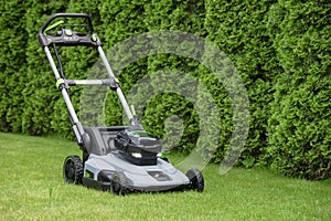 Electric lawn mower on a green grass in the backyard