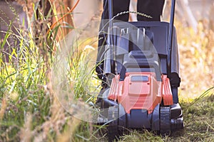 Electric lawn mower mows grass in the garden