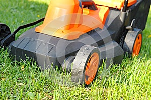 Electric lawnmower on green grass
