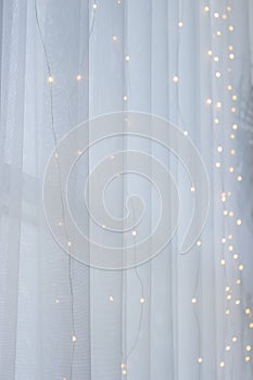 Electric light line on white window curtain. Holiday decoration. Abstract Christmas background. Festive interior design.