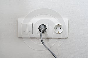 Electric light switch and socket on the empty wall, electrical power socket and plug switched. The concept of energy savings