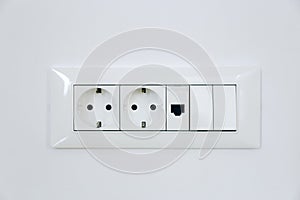 Electric light switch and socket on the white wall