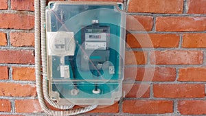 An electric meter on a brick wall that measures energy consumption. Watt-hour measurement tool on brick wall, green with