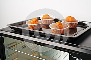 Electric mini oven and baked hot muffins close up photo