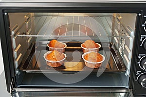 Electric mini oven and baked hot muffins close up photo